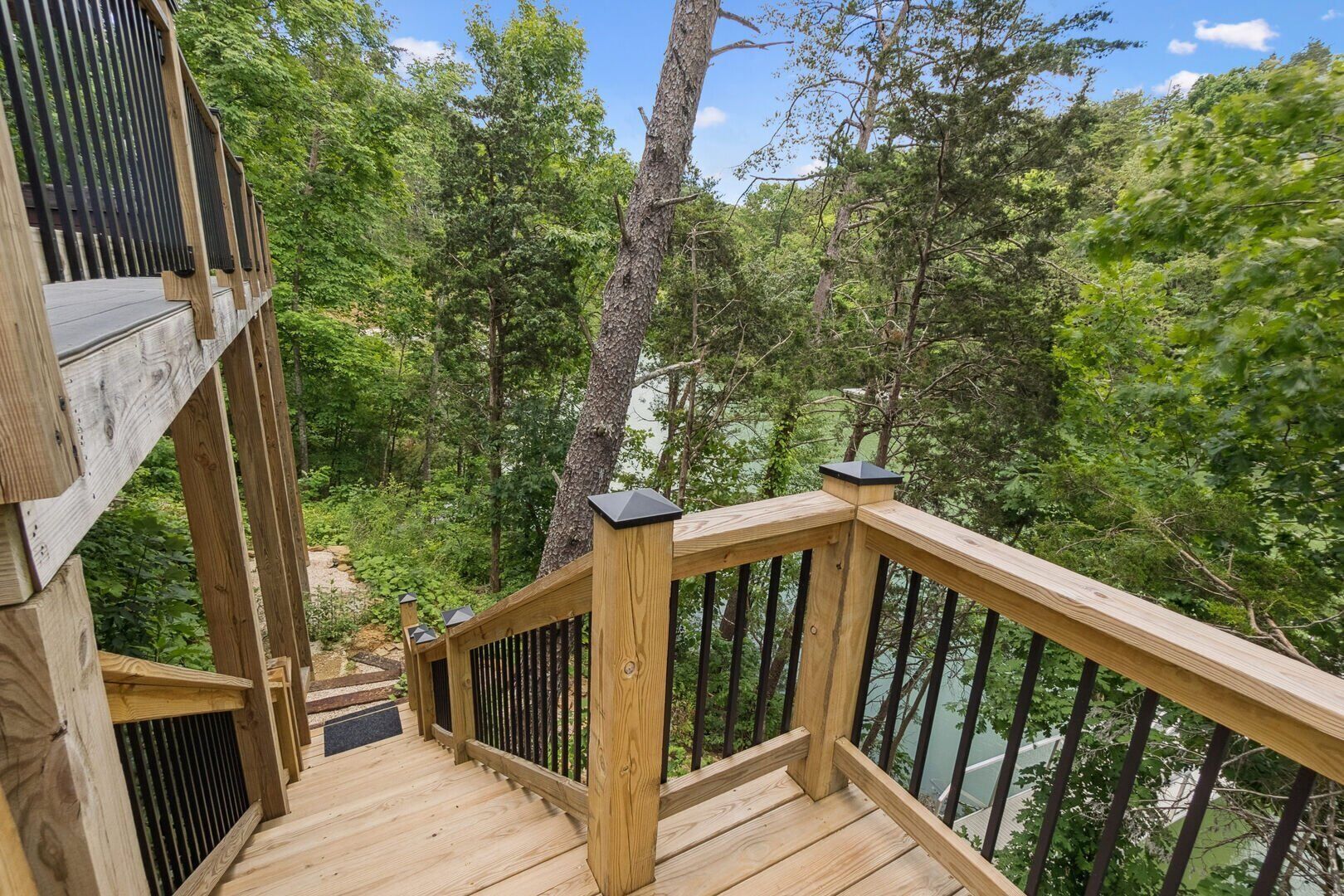 A wooden deck with a railing overlooking a forested area.