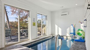Ein Schwimmbecken mit Metallleiter, eine Sonnenterrasse mit einem Stuhl und Blick auf Bäume.