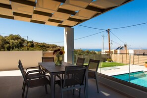 A covered outdoor area with a pool, dining table, and chairs.