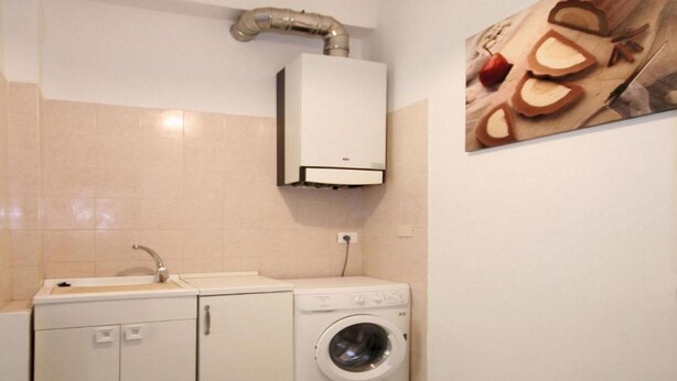 A compact laundry room with a washing machine, a sink, and a cabinet.