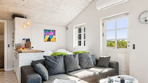 Ett modernt vardagsrum med en grå soffa, ett litet vitt bord och en färgstark, abstrakt tavla på väggen.