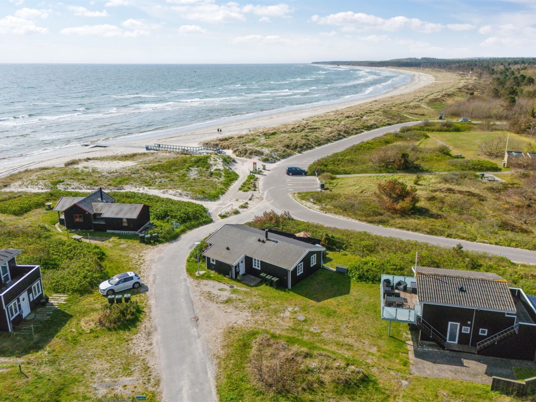 A coastal property with a road leading to a beach, houses, and a pier.