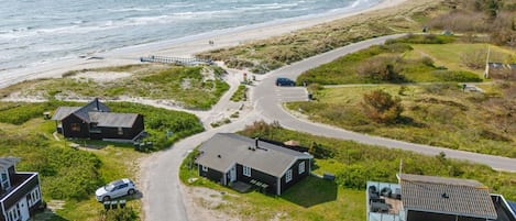 A coastal property with a road leading to a beach, houses, and a pier.