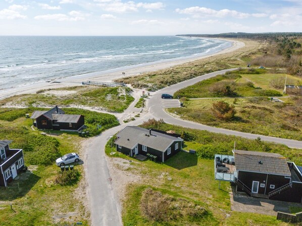 A coastal property with a road leading to a beach, houses, and a pier.