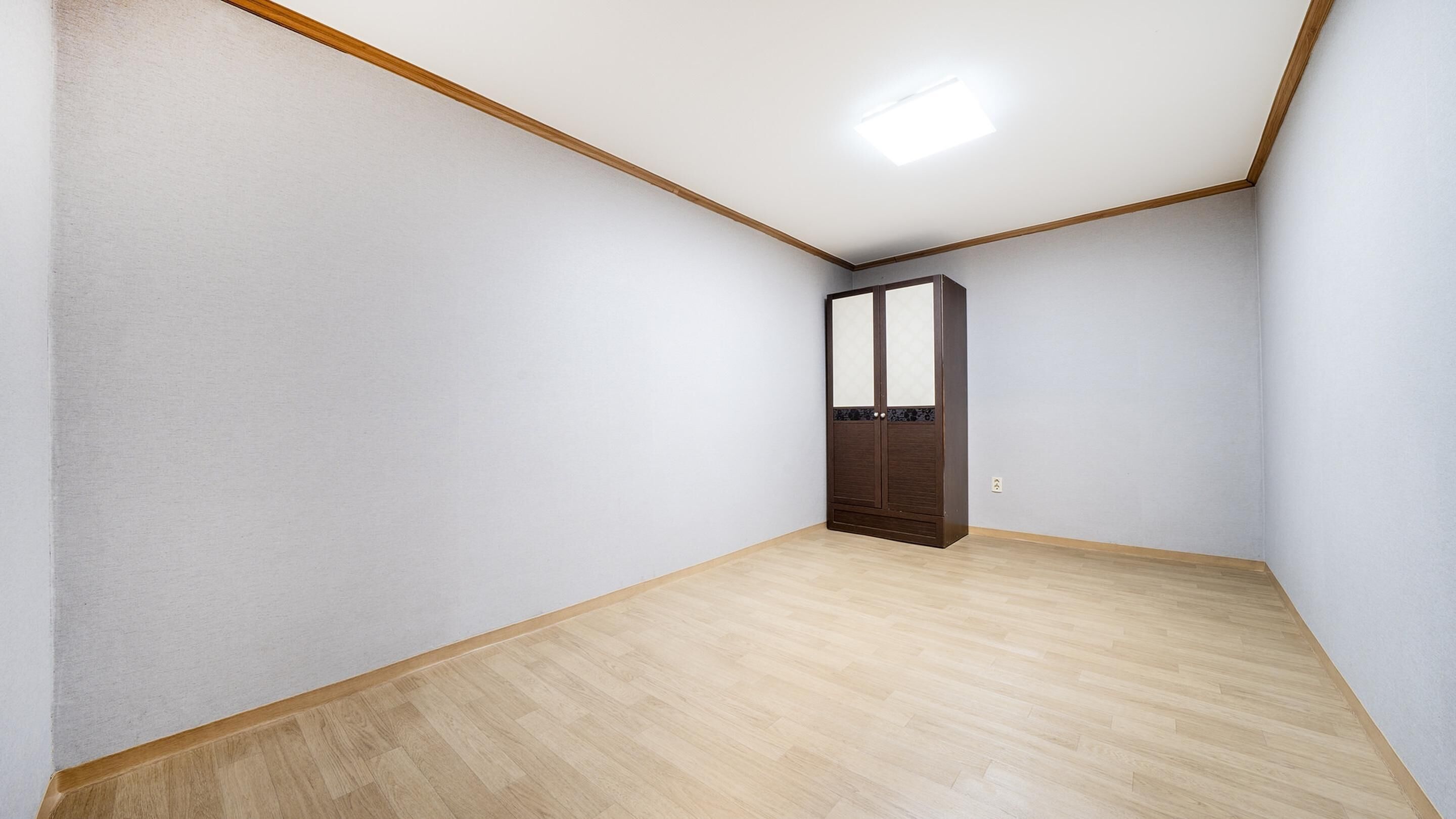 A room with a wooden floor, white walls, and a ceiling with a recessed light.