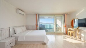 A hotel room with a bed, a TV, a wooden dresser, and a balcony with a view.