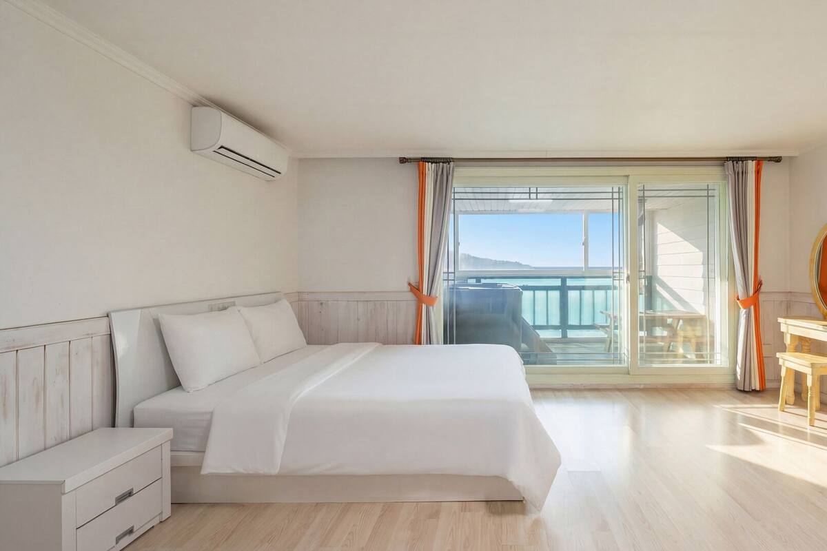 A hotel room with a bed, a TV, a wooden dresser, and a balcony with a view.