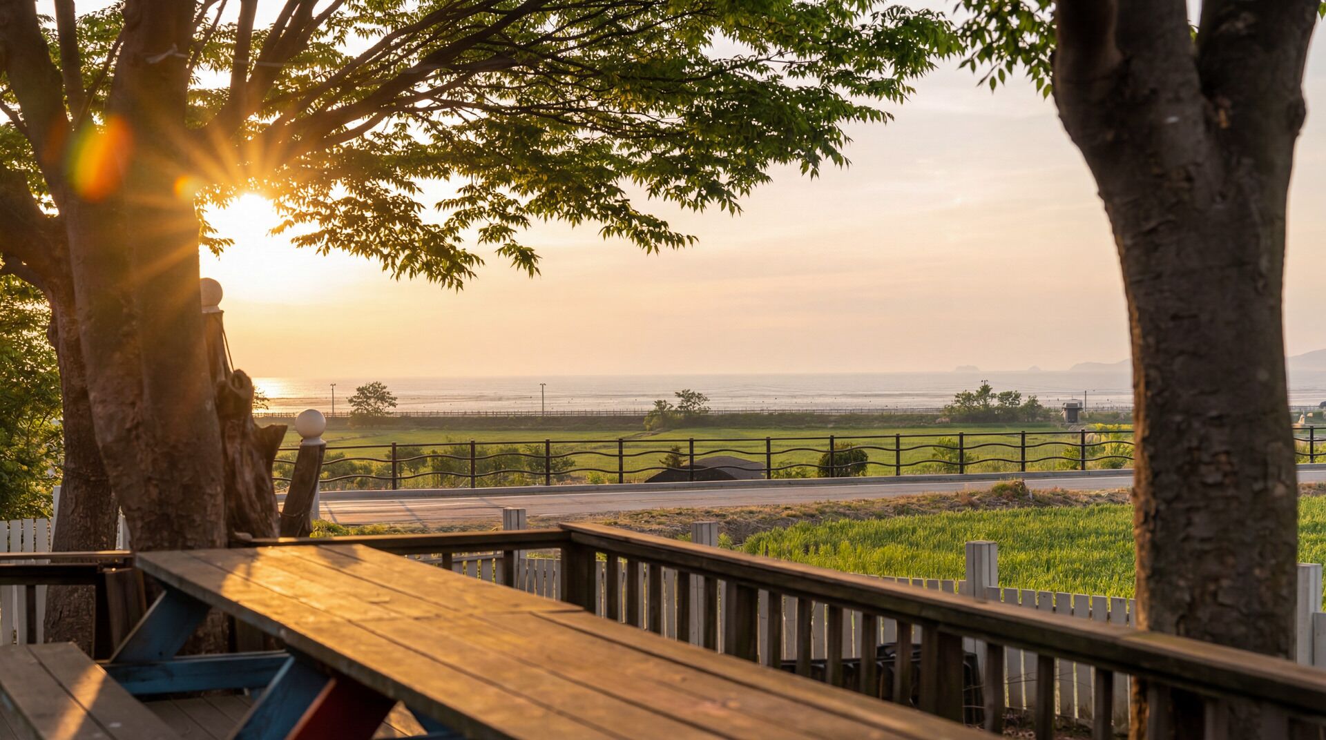 A wooden deck with a view of the ocean and a fence in the background.