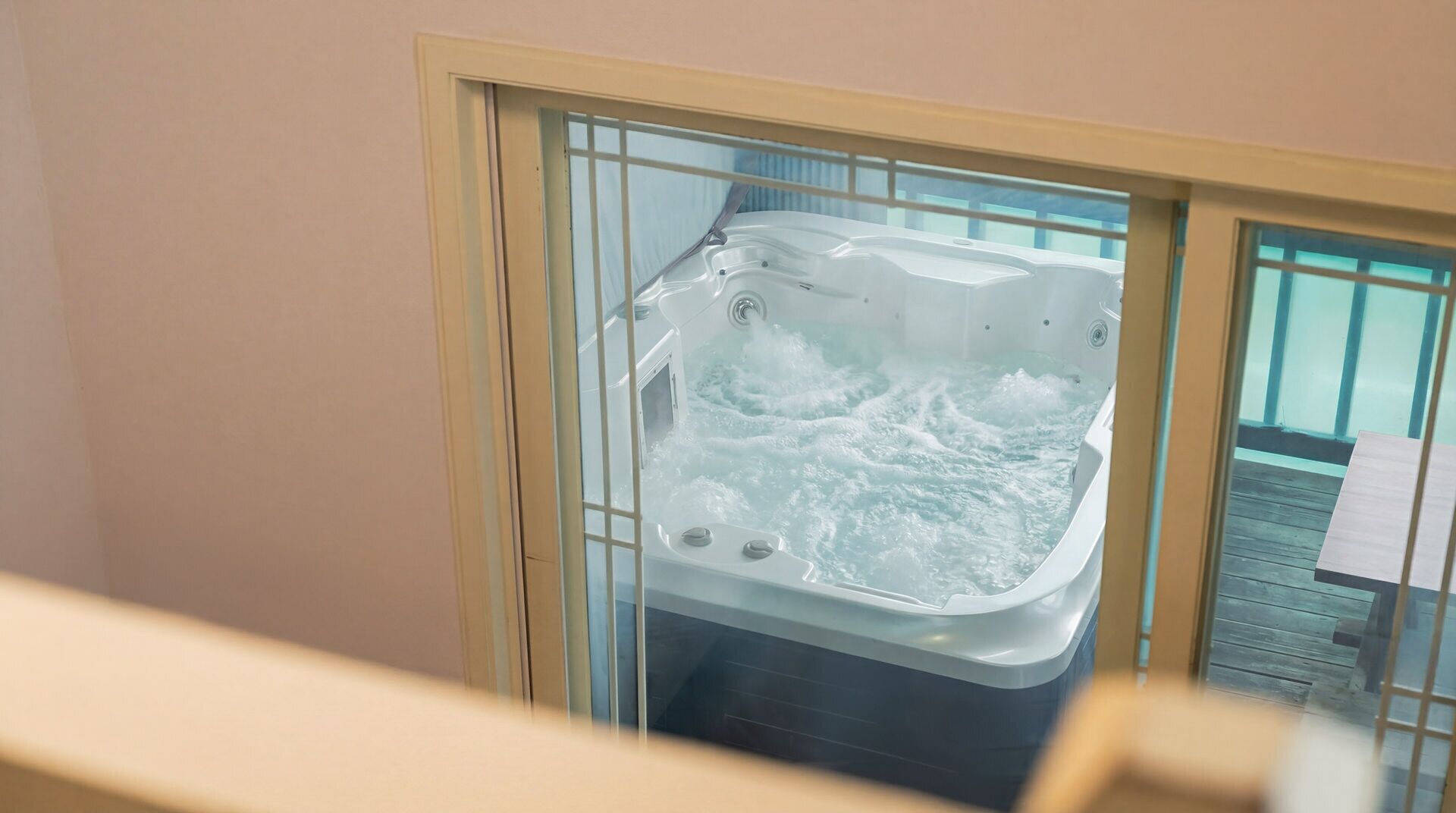 Un jacuzzi con chorros de agua, una terraza de madera en el exterior y un cerramiento de cristal.