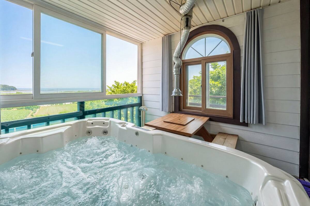 A hot tub with a wooden deck and a view of the countryside.