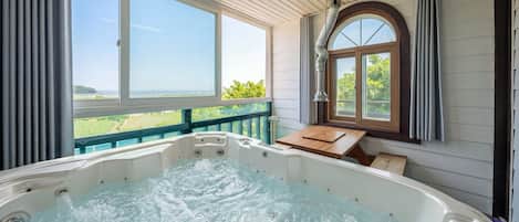 Ein Whirlpool mit Holzterrasse und Blick ins Grüne.