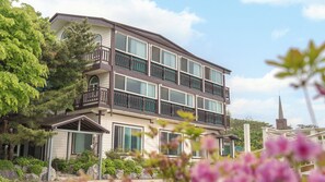 A multi-story hotel with balconies, large windows, and a church spire in the background.