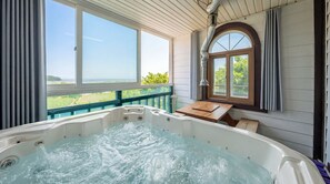 A hot tub with a wooden deck and a view of the countryside.