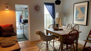 A cozy living room with a wooden coffee table, a fluffy rug, and a dining area with a wooden table and chairs.