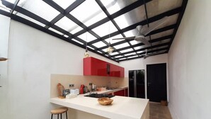 A modern kitchen with a central island, red cabinets, and a black ceiling structure. - Villa Adam Seminyak (Seminyak)