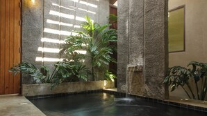 A spa area with a water feature, stone walls, and potted plants.
