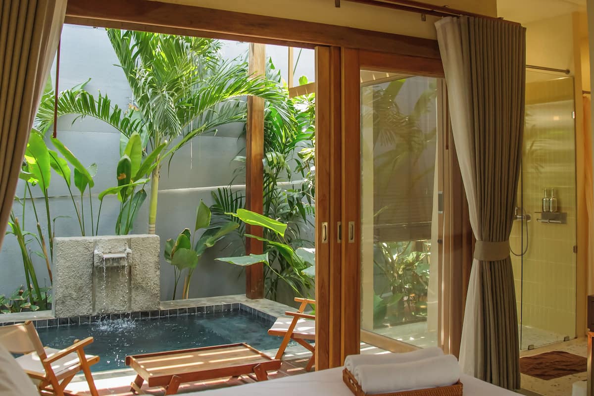 Une chambre d’hôtel avec un lit, une petite piscine et une vue sur la verdure.