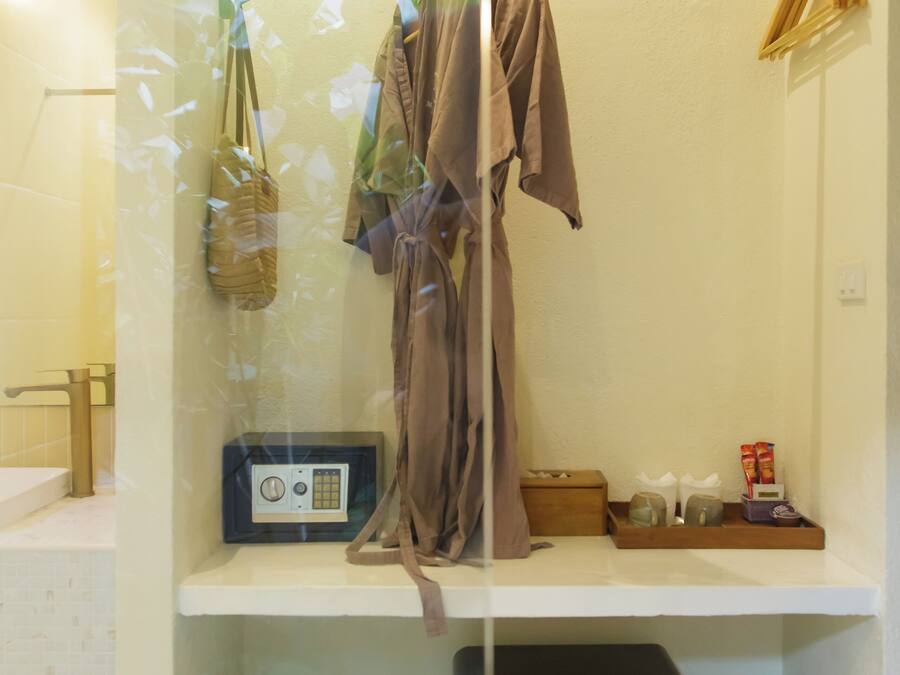 Un baño con un perchero, una radio, un cubo de basura y una maleta.