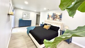 Un dormitorio con cama, cómoda, espejo y un cuadro en la pared.