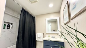 Un baño con cortina de ducha, lavabo con espejo y artículos de aseo en la pared.