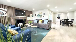 Una sala de estar moderna con un sofá, una mesa de centro y una chimenea. Hay un comedor con una mesa y sillas.