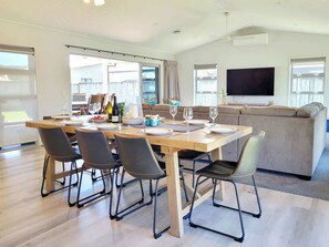 Ein modernes Wohnzimmer mit Essbereich, einer Couch und einem Flachbildfernseher.
