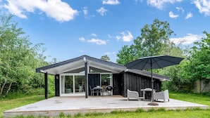 A modern house with a covered patio, outdoor seating, and a barbecue area.
