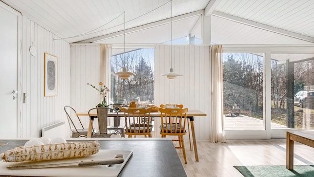 A modern kitchen with a dining area, large windows, and a view of the outdoors.