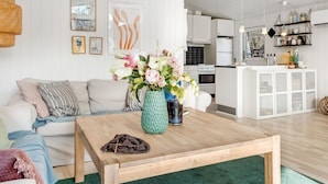 A modern living room with a wooden coffee table, a sofa, and a kitchen in the background.