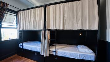 Habitación con dos literas, piso de madera y ventana con cortinas.