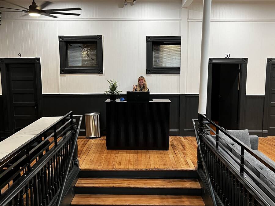 A staircase leading to a reception area with a desk, two framed windows, and a ceiling fan.