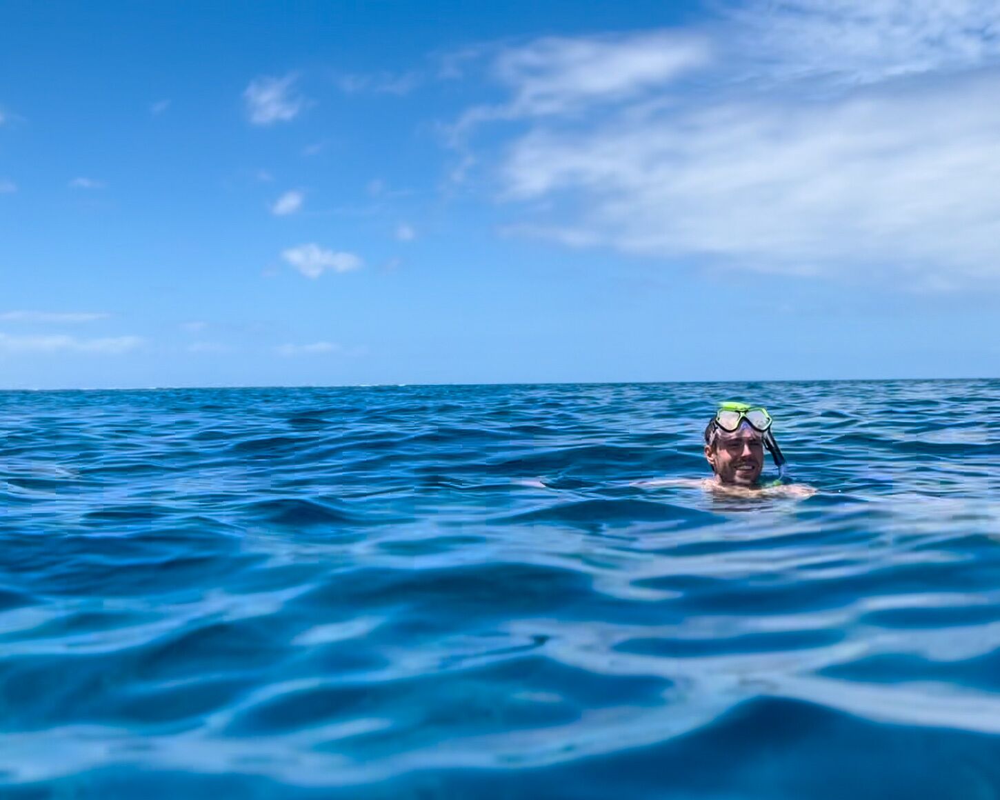 A person swimming in the ocean with a clear sky in the background.