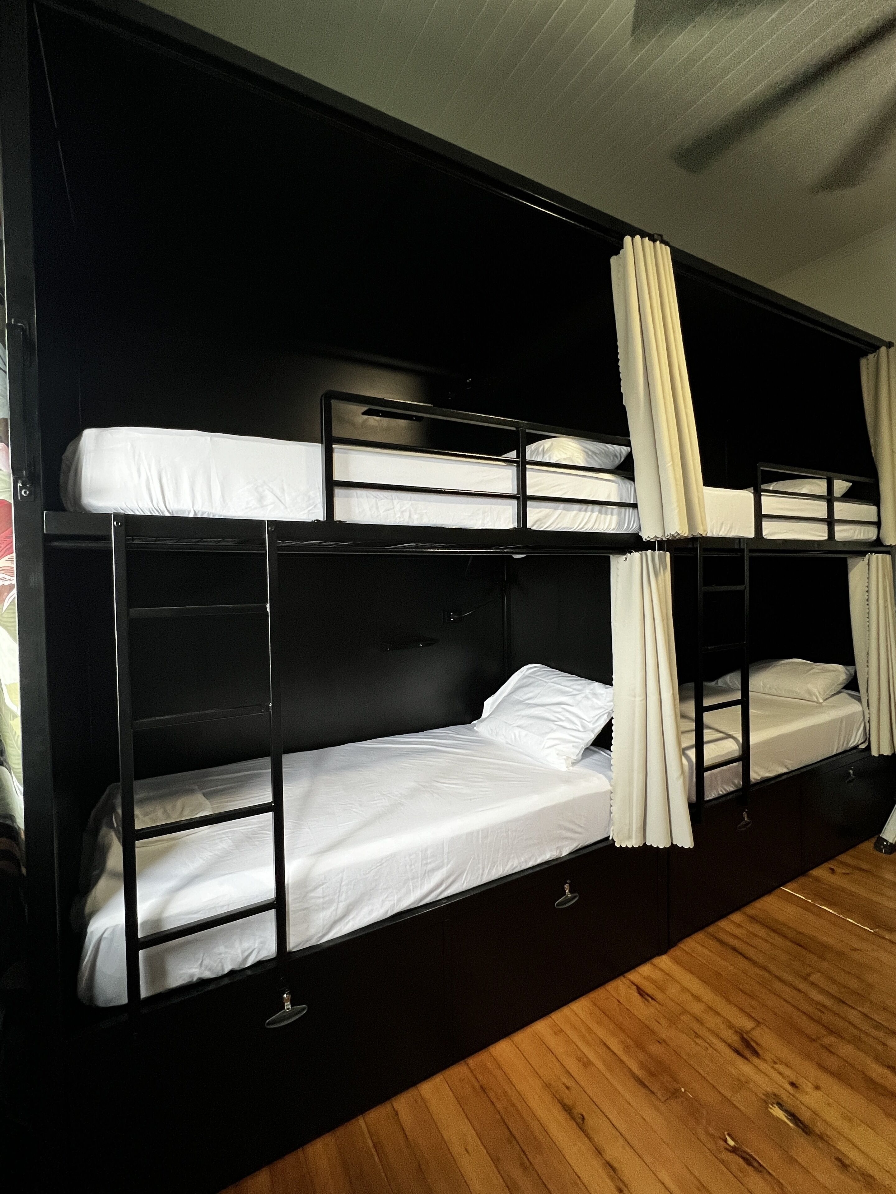 A bunk bed room with a wooden floor and black walls.