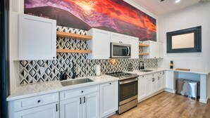 Una cocina moderna con armarios blancos, horno de acero inoxidable y microondas.