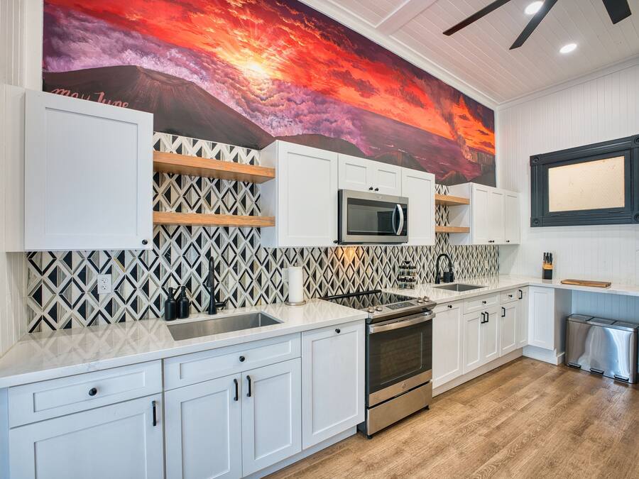 A modern kitchen with white cabinetry, a stainless steel oven, and a microwave.