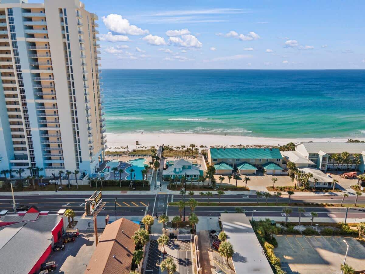 A coastal hotel with a swimming pool, beachfront view, and multiple buildings.