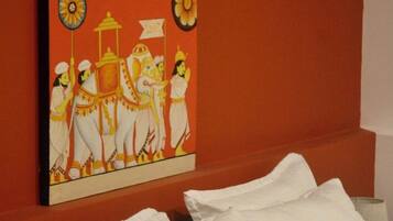 Una habitación de hotel con una cama, almohadas blancas y una pared con un cuadro de colores.