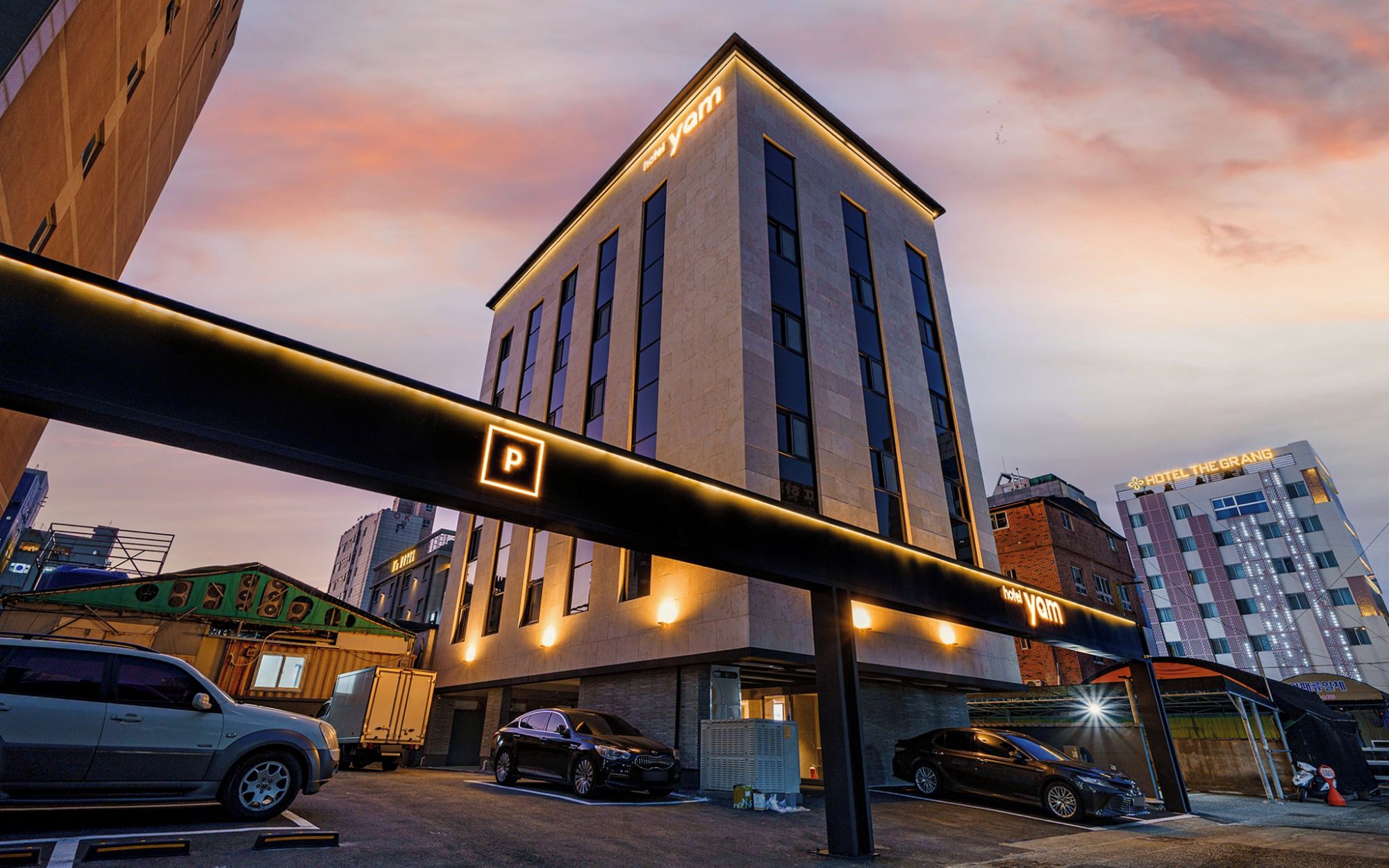 A modern building with a prominent 'hotel yam' sign, a parking sign, and a visible entrance.