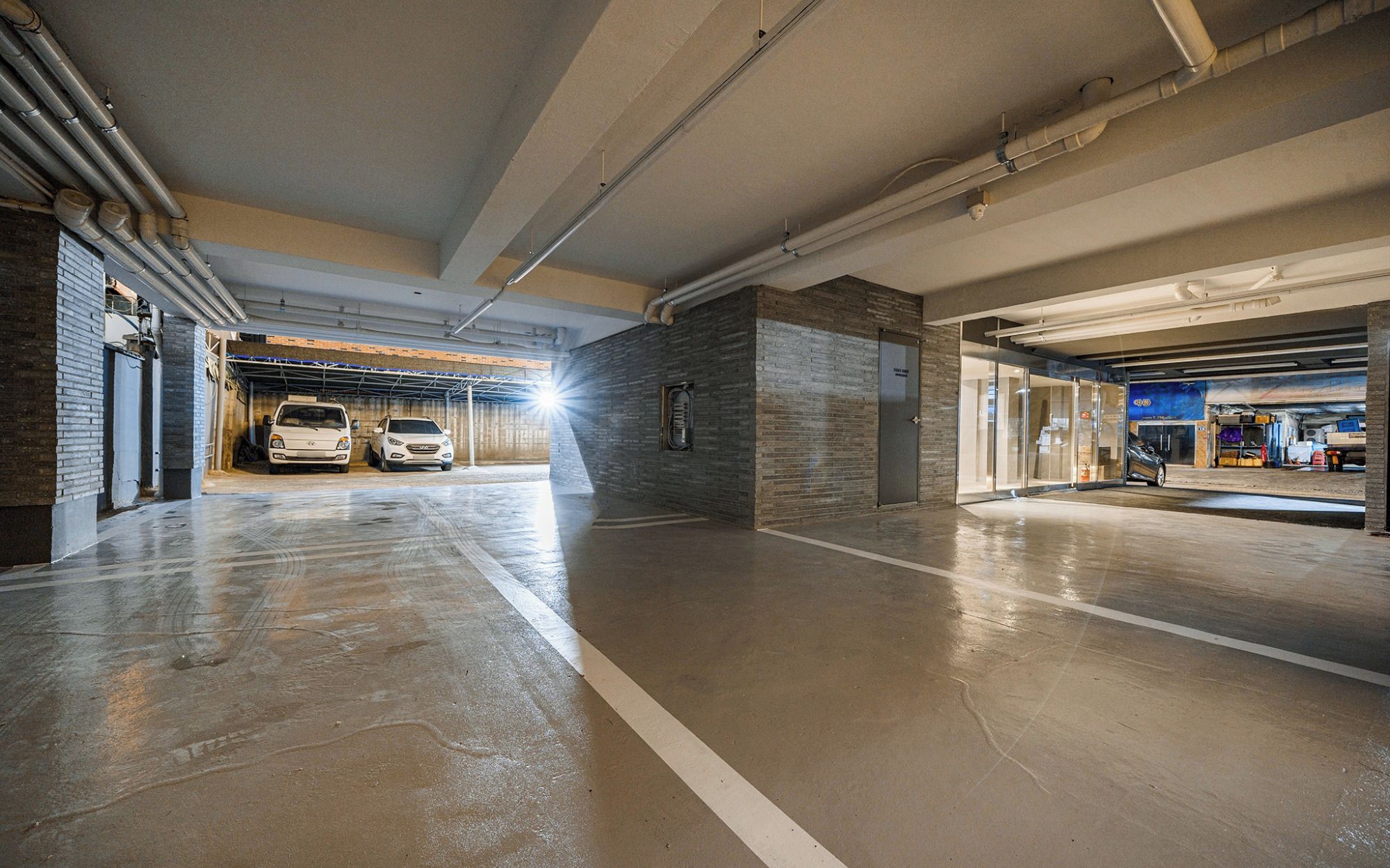 Een parkeergarage met meerdere verdiepingen, een gladde vloer en zichtbare leidingen.