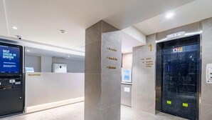 Een receptie met een zelf incheck systeem, een receptiebalie en een lift.