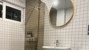 Een badkamer met douche, wastafel, toilet en spiegel.