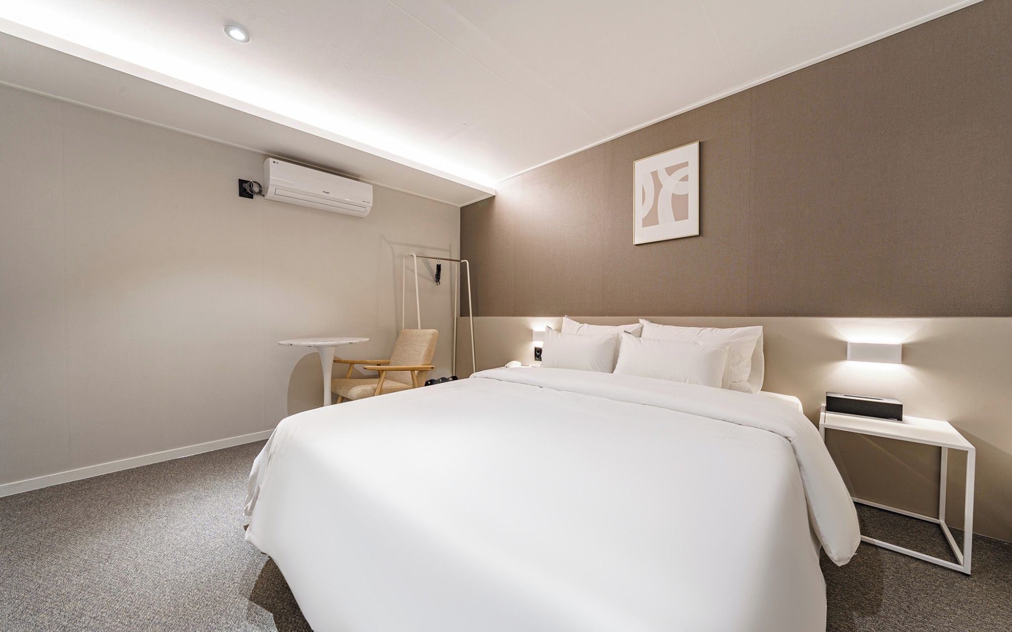 Een hotelkamer met een groot bed, een nachtkastje, een stoel en een airconditioning op de muur.