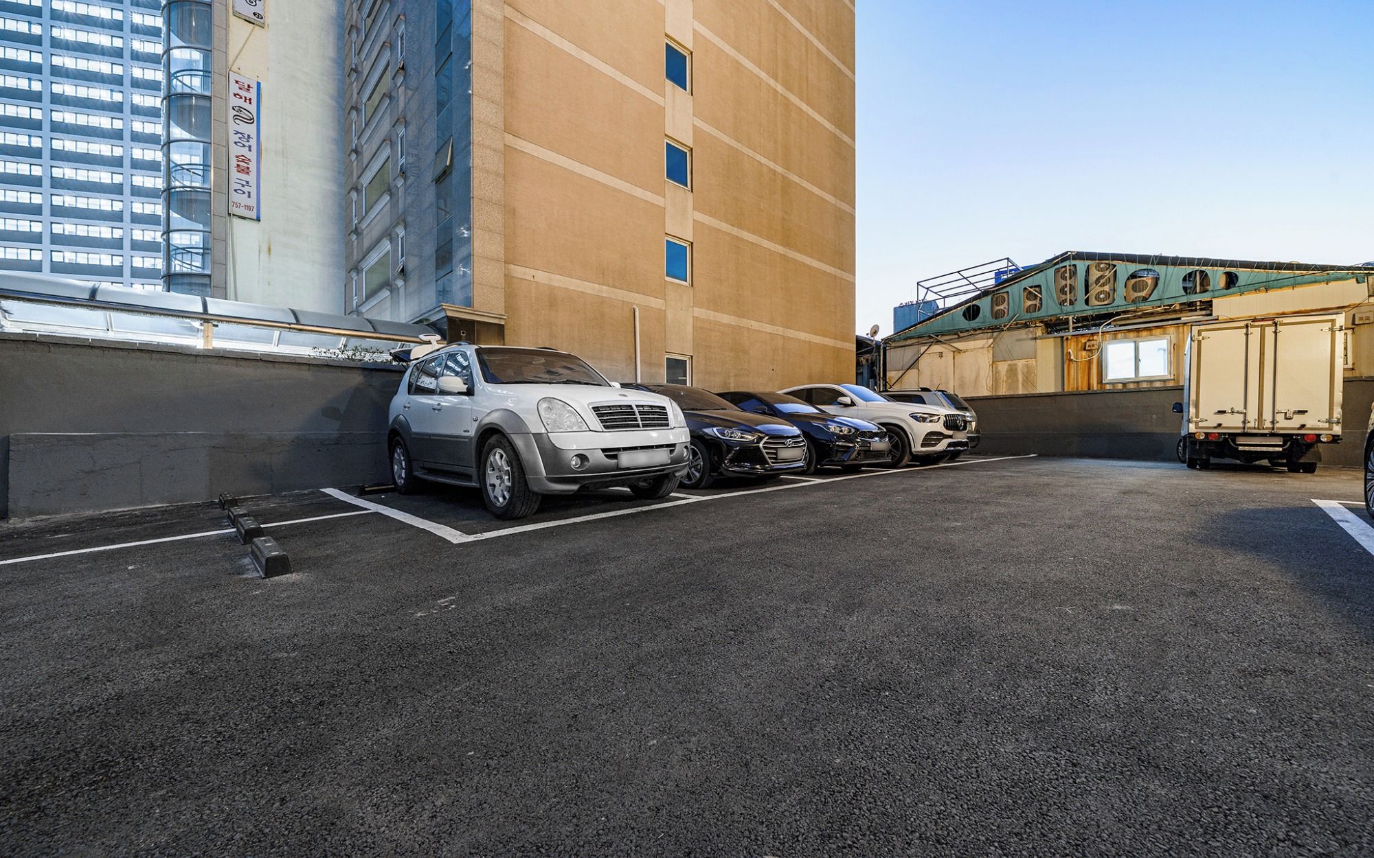 A parking lot with several cars and a building in the background.