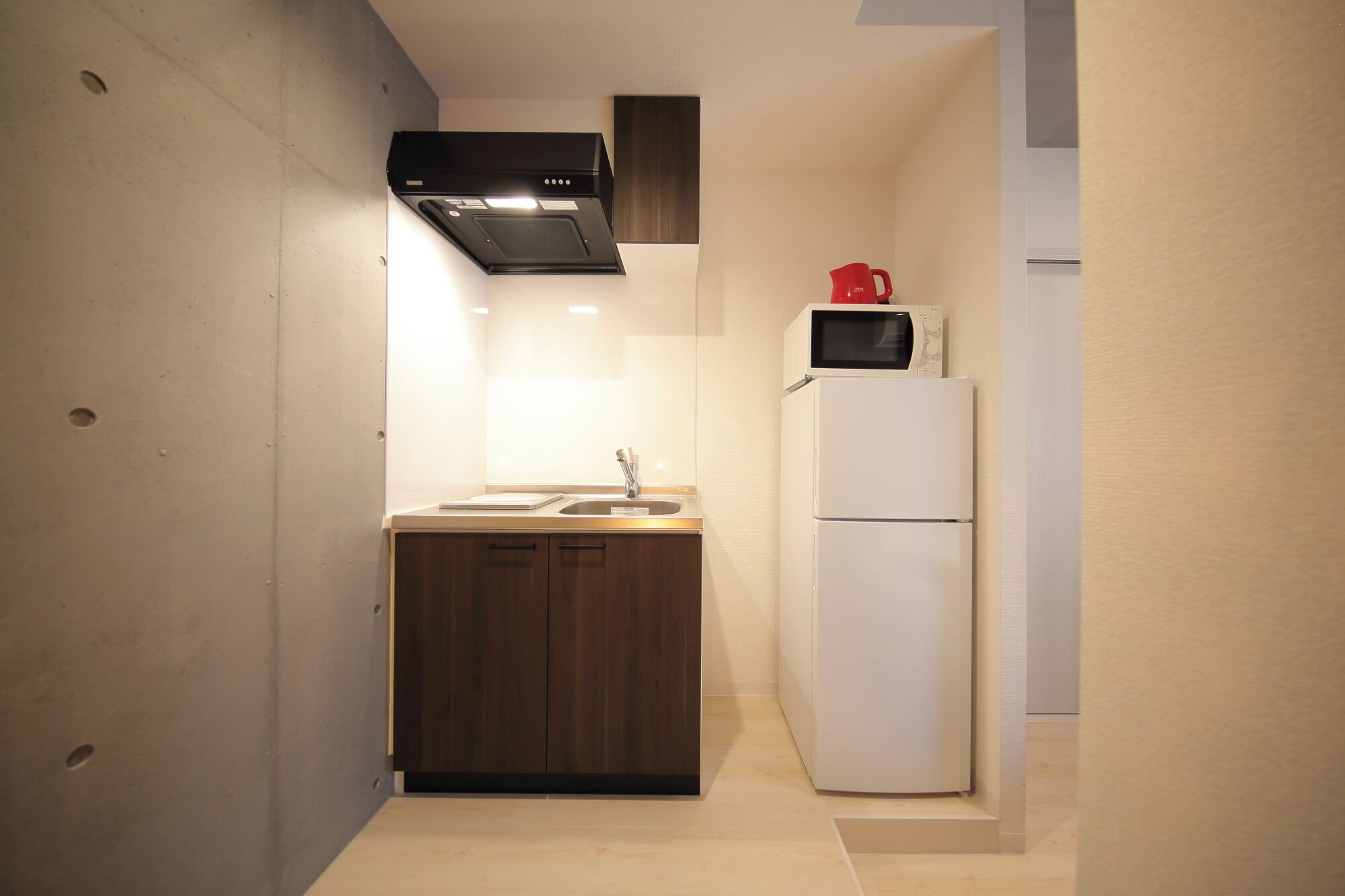 A compact kitchen with a wooden countertop, a sink, a stove, and a refrigerator.