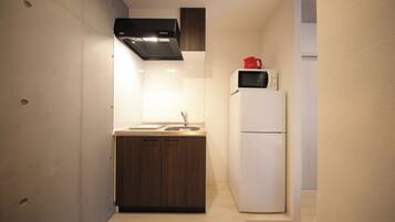A compact kitchen with a wooden countertop, a sink, a stove, and a refrigerator.