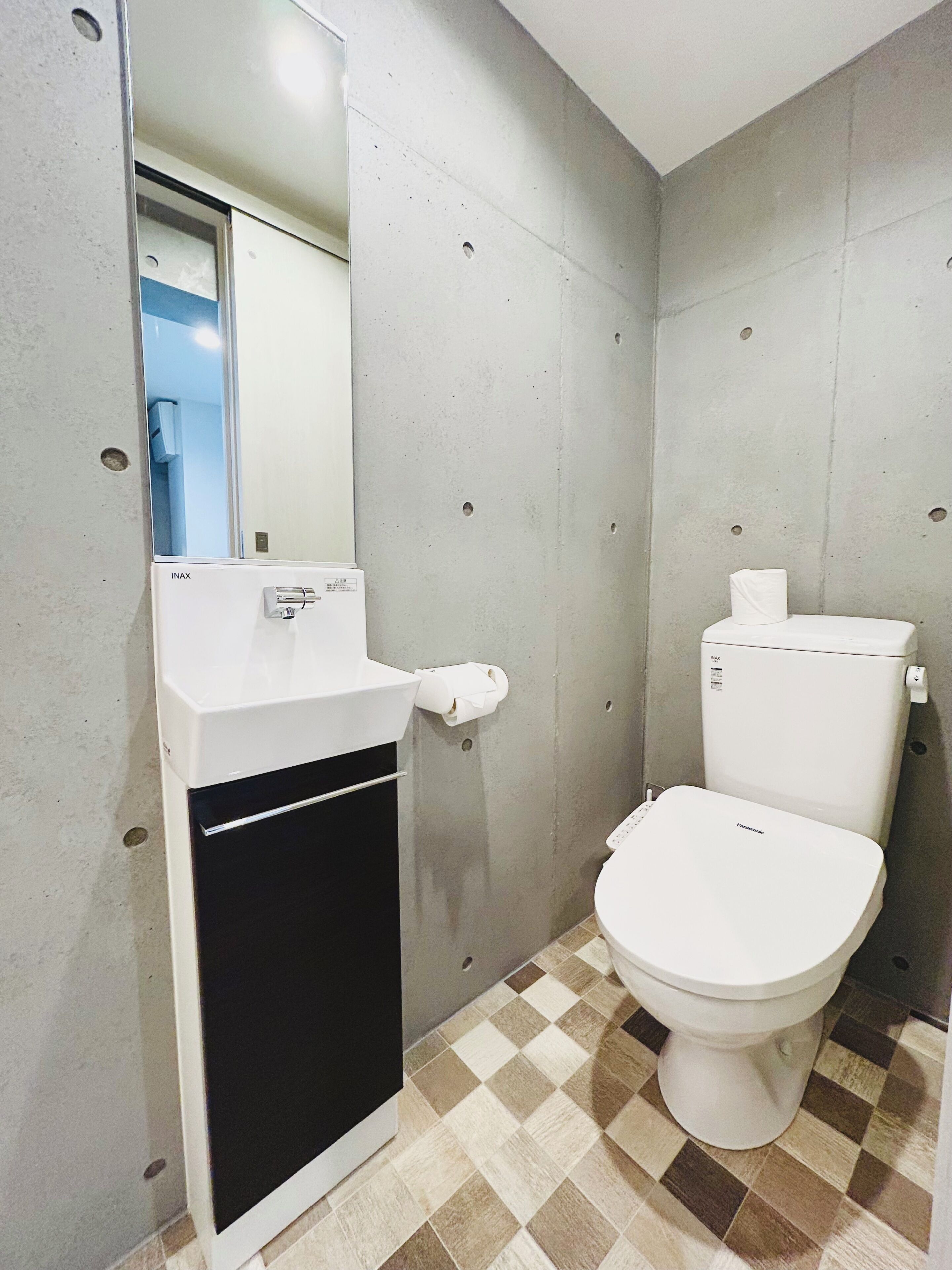 A bathroom with a white toilet, a sink with a mirror, and a checkered floor.