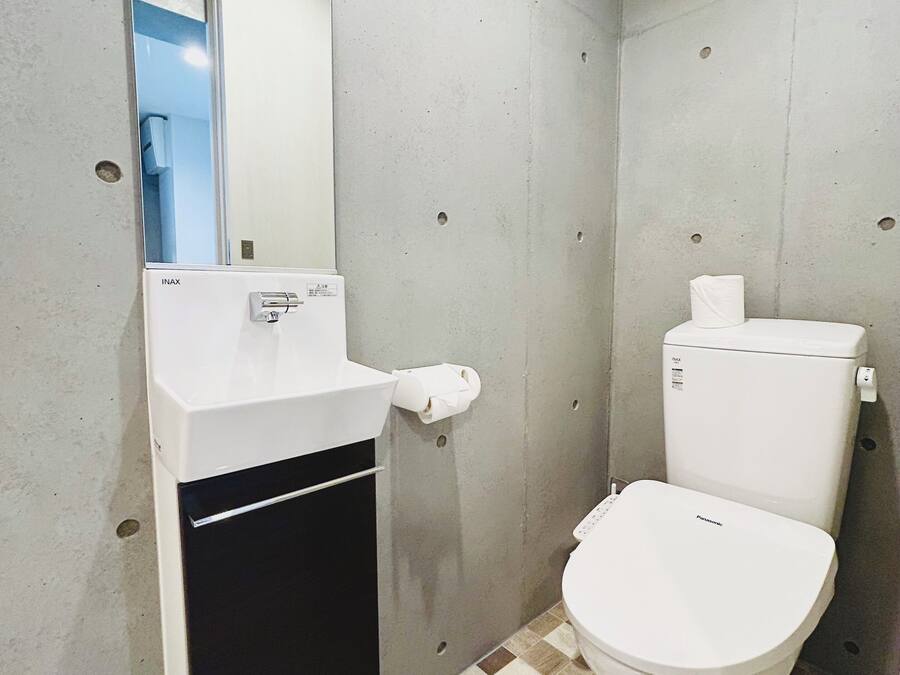 A bathroom with a white toilet, a sink with a mirror, and a checkered floor.