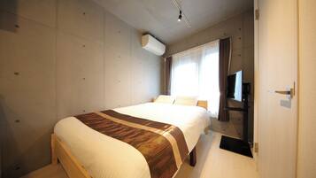 A hotel room with a large bed, a flat-screen TV, and a window with curtains.