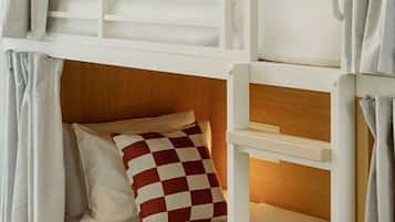 A bunk bed with a wooden headboard, a lower bed with a checkered pillow, and a ladder.