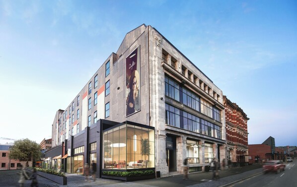 Un edificio moderno con ventanas amplias, un letrero llamativo y una combinación de estilos arquitectónicos.